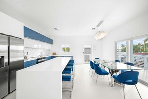 Une cuisine moderne dotée d’un îlot central, d’appareils électroménagers en acier inoxydable et de touches de couleur bleue.