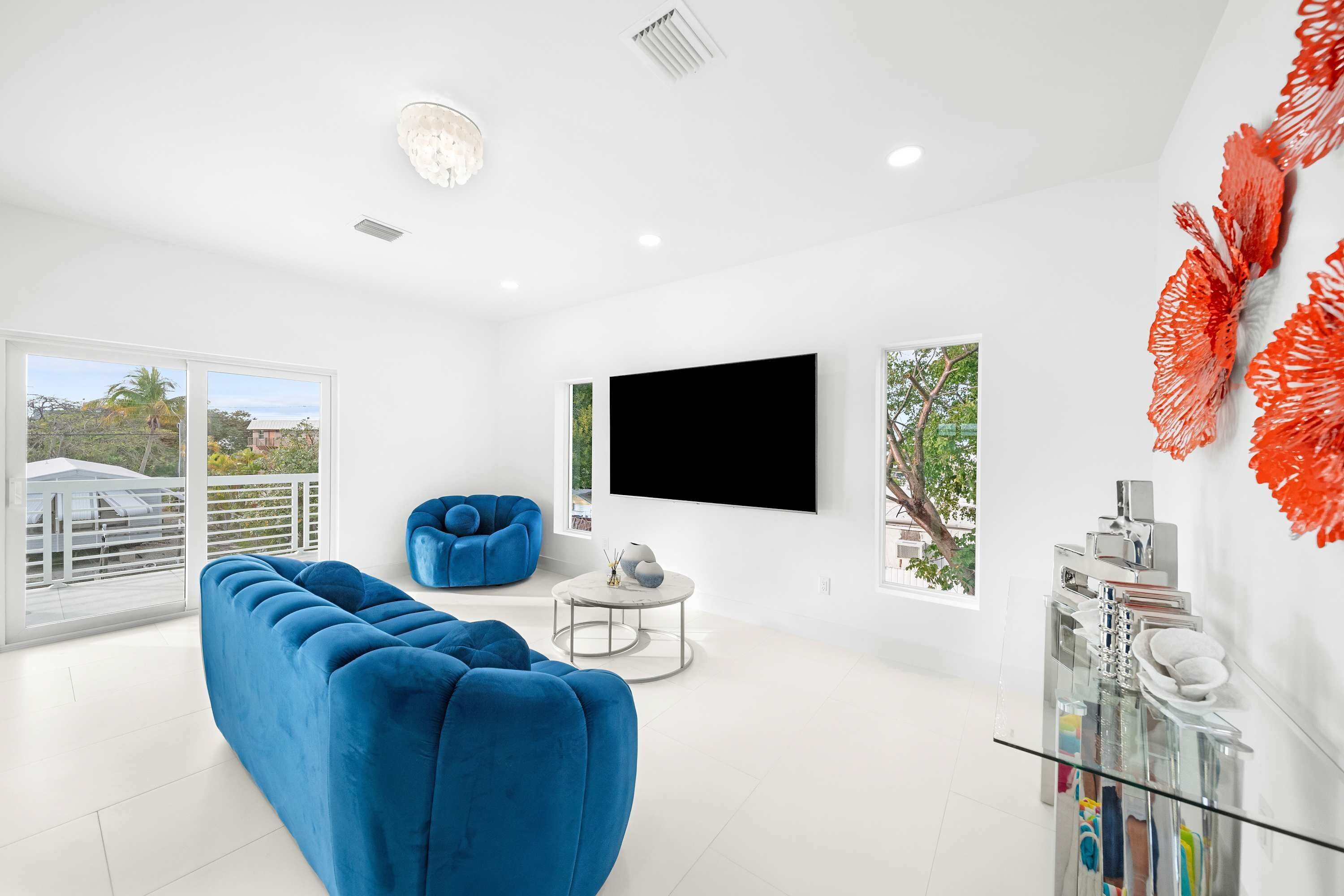Ein modernes Wohnzimmer mit einem blauen modularen Sofa, einem runden Couchtisch und einem großen Flachbildfernseher an der Wand.