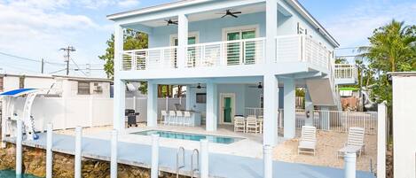 A two-story house with a pool, a balcony, and a covered outdoor area.