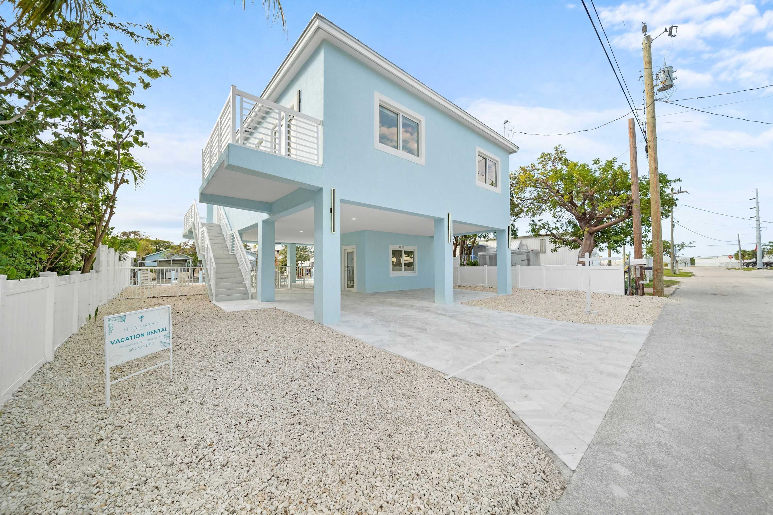 A light blue vacation rental with a covered patio and a staircase leading to an upper deck.
