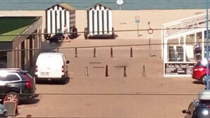 A parking area with a view of the sea, a kiosk, and a few parked cars. - Room Kabine 1 (Koksijde)