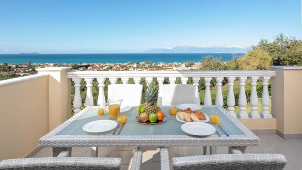 Une table dressée pour le petit-déjeuner, avec vue sur la mer et les montagnes.
