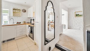 A modern kitchen with white cabinetry, a built-in oven, and a large mirror.