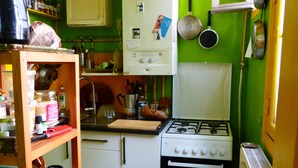 A compact kitchen with a gas stove, white cabinets, and a green wall. - Charming apartment in Belleville (Paris)