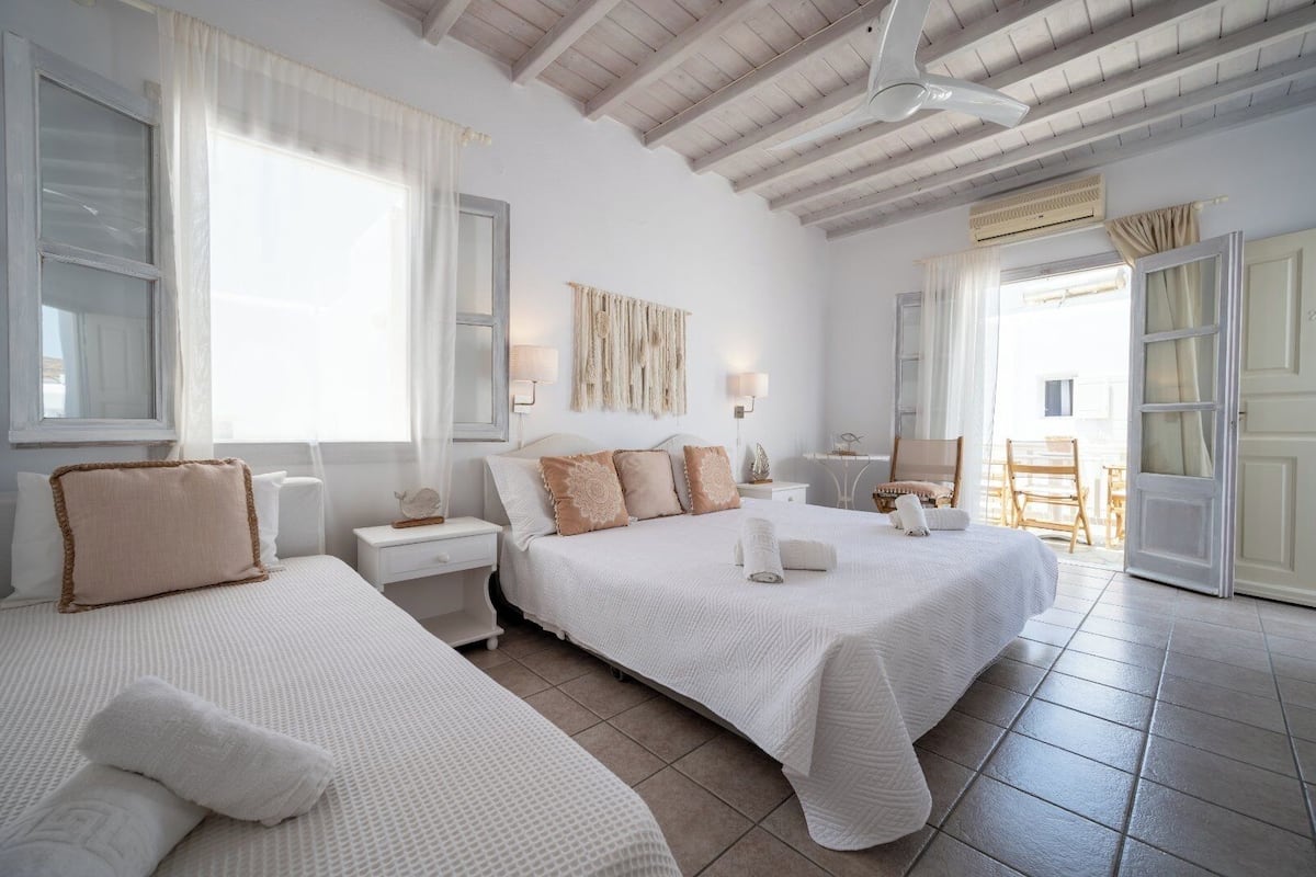 A hotel room with two beds, a ceiling fan, and a view of the outside.