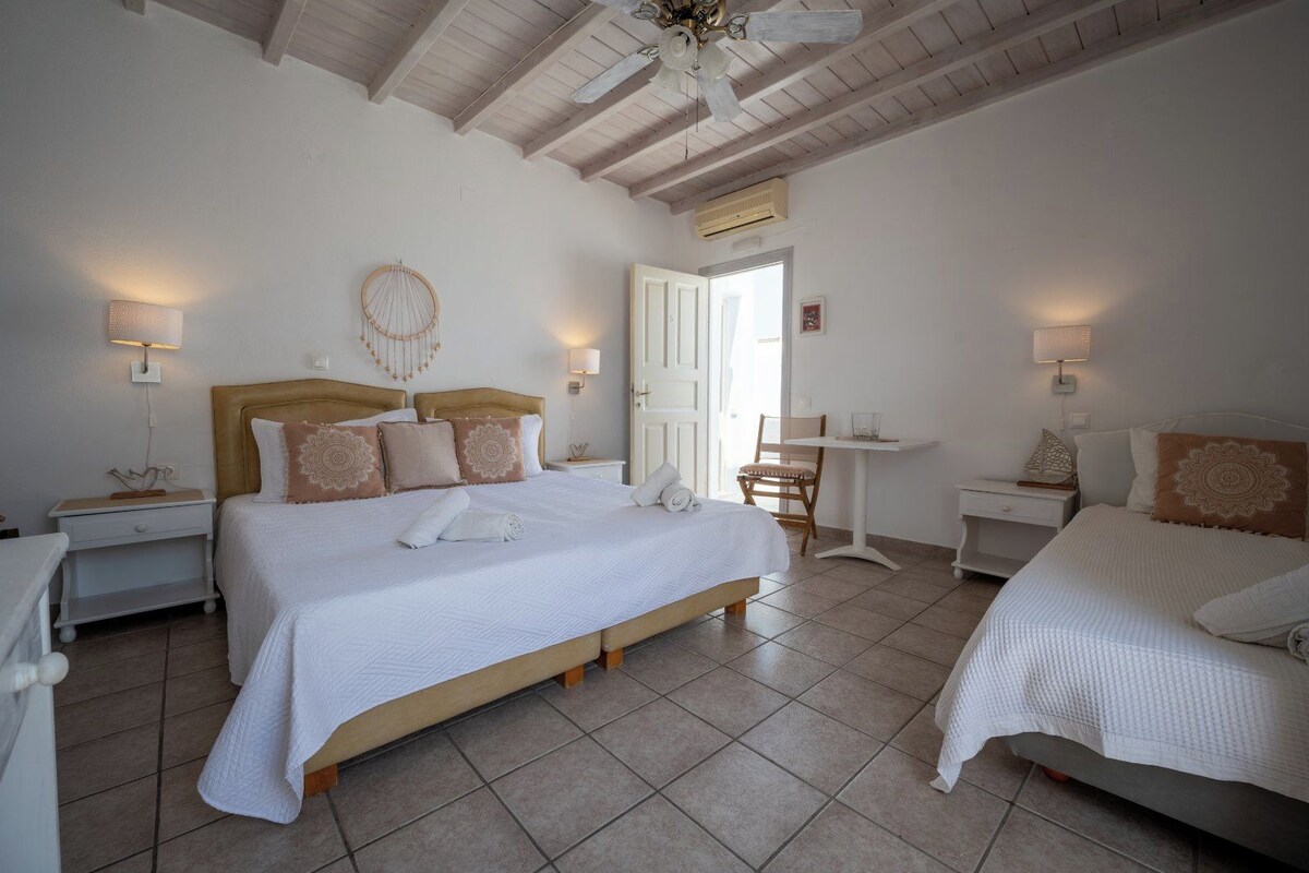 A bedroom with two beds, a small table, and a chair.