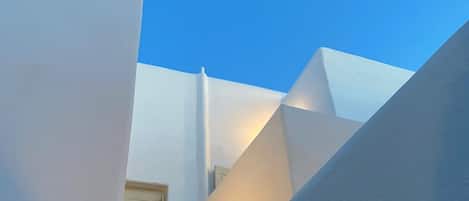 Um beco estreito entre edifícios brancos, com céu azul intenso.