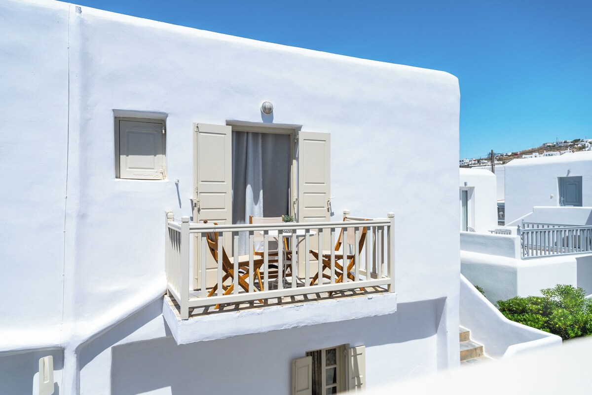 A white building with a balcony, a window, and a door.