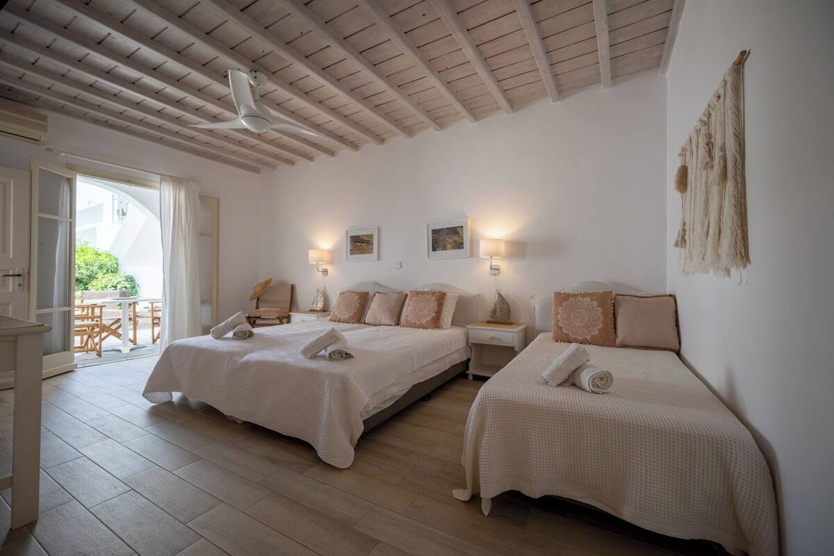 A bedroom with two beds, a ceiling fan, and a view of the outdoors.