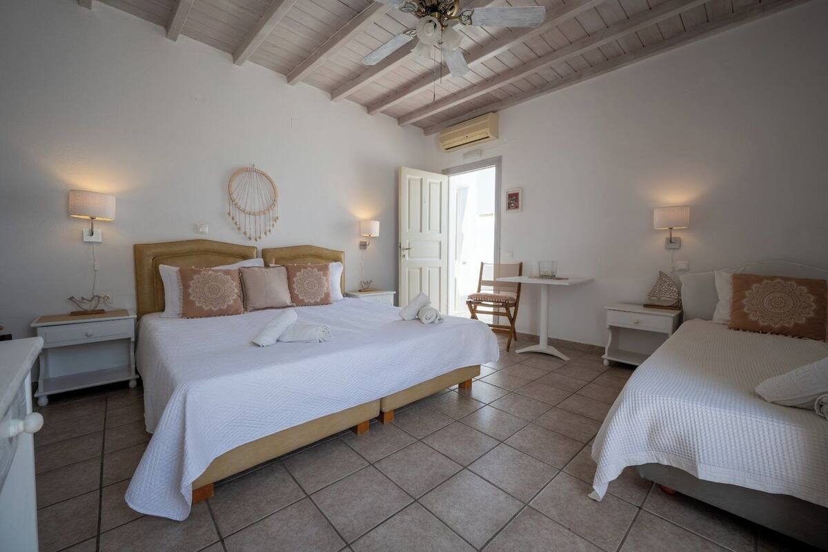 A bedroom with two beds, a small table, and a chair.