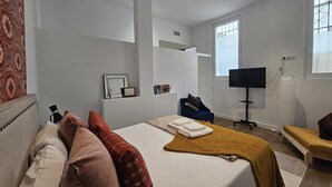 Une chambre d’hôtel avec un lit, une télévision, une chaise, un bureau et une fenêtre.