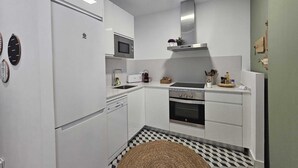 Une cuisine moderne avec des meubles blancs, un four à micro-ondes, une cuisinière et un évier.