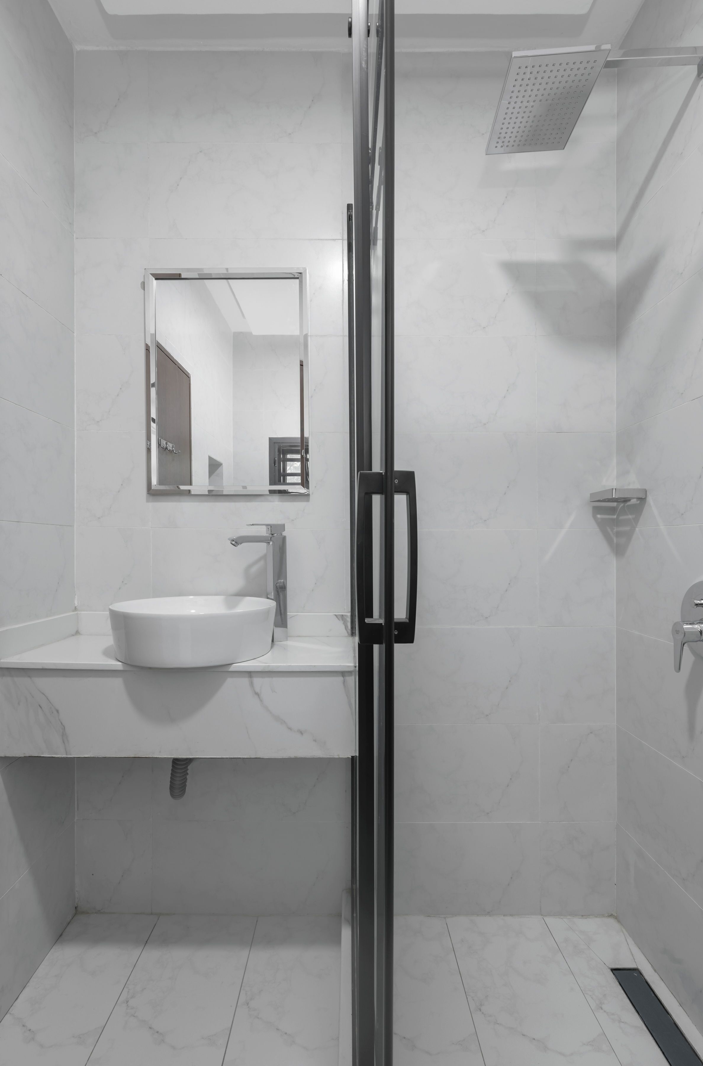 A modern bathroom with a glass-enclosed shower, a white sink, and a mirror above the sink.