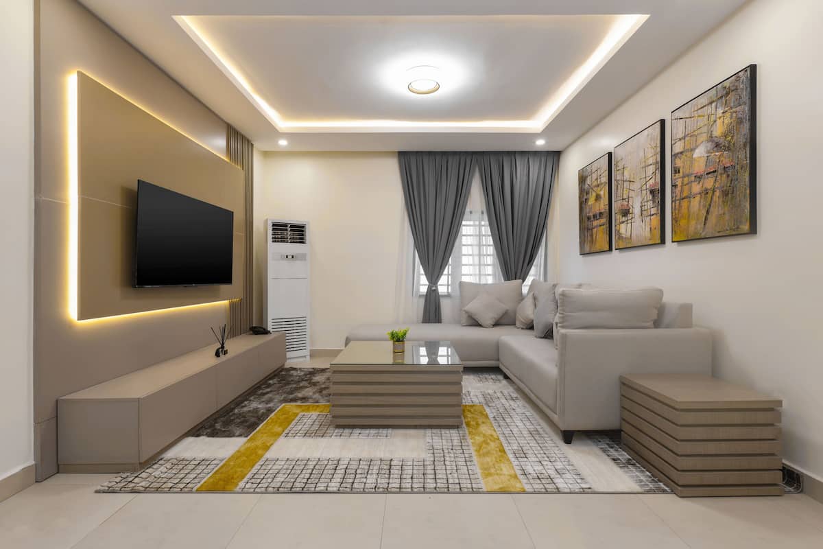 Una sala de estar moderna con un televisor de pantalla plana, un sofá, una mesa de centro y obras de arte en las paredes.