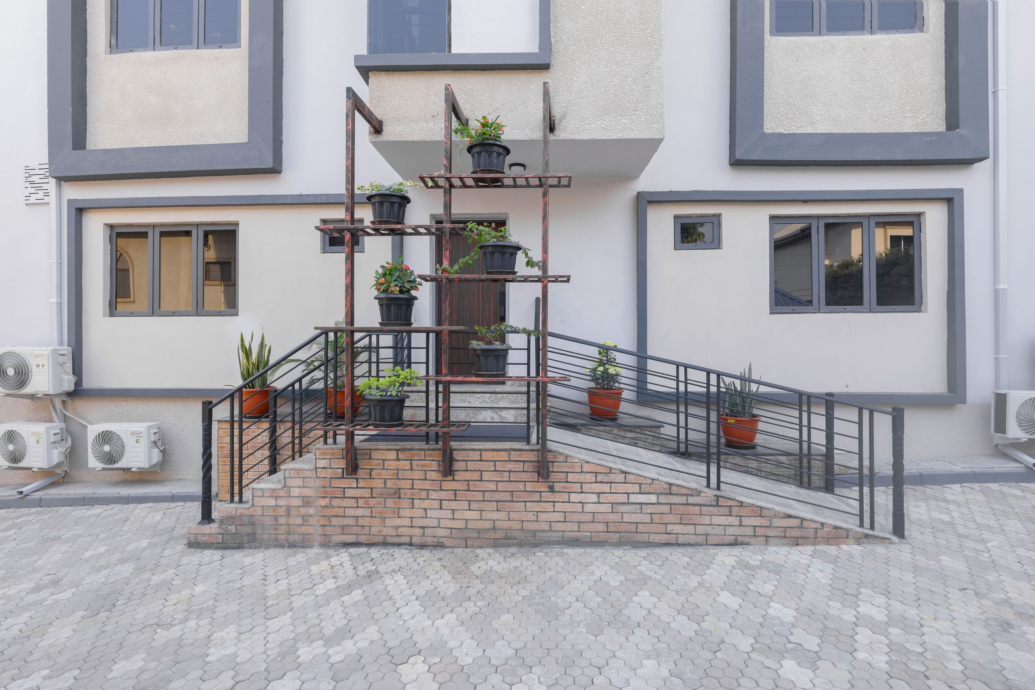 A building with a brick staircase, metal railings, and potted plants.