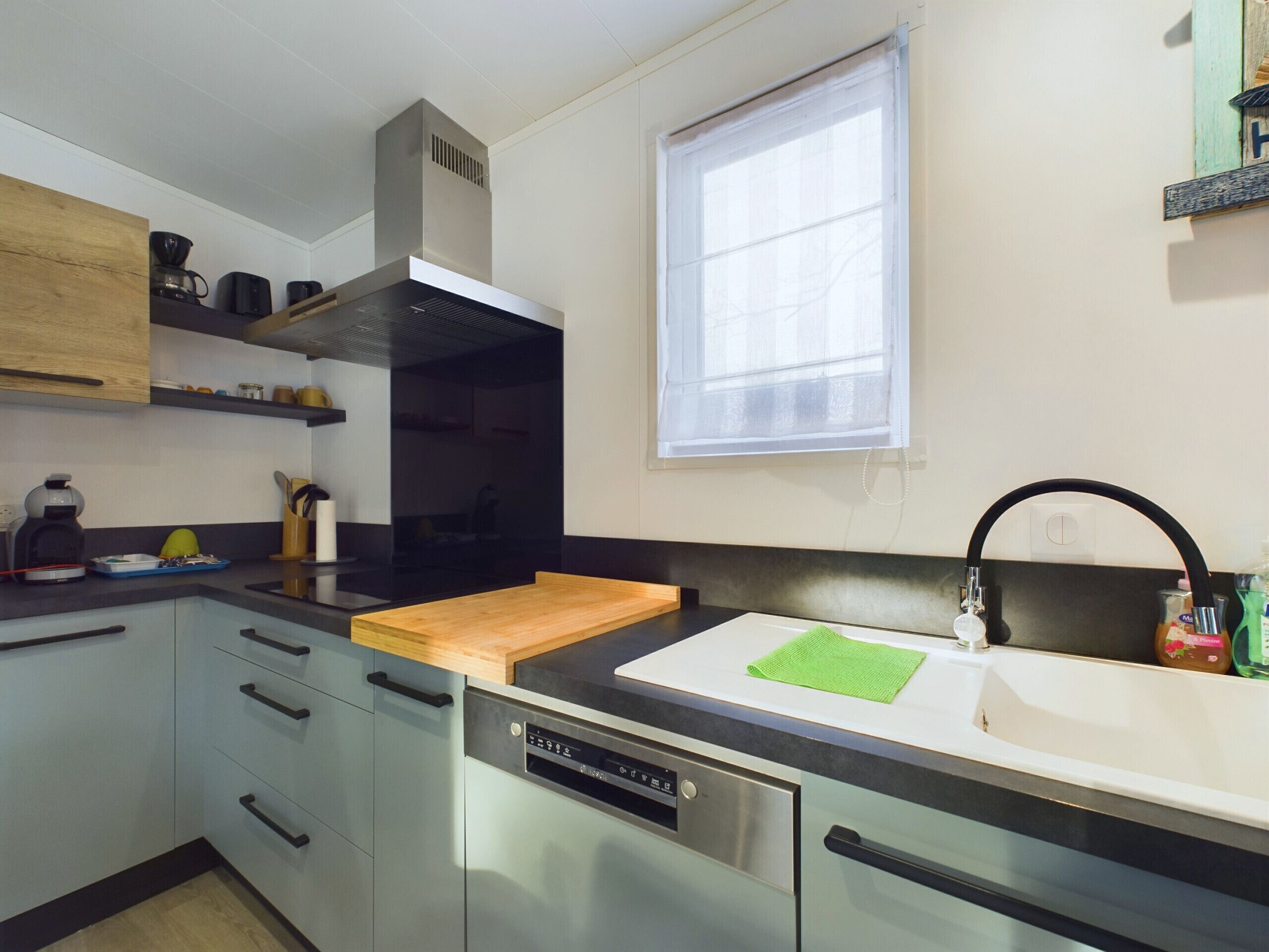 Una cocina moderna con lavavajillas, encimera de madera, un lavabo y una ventana.