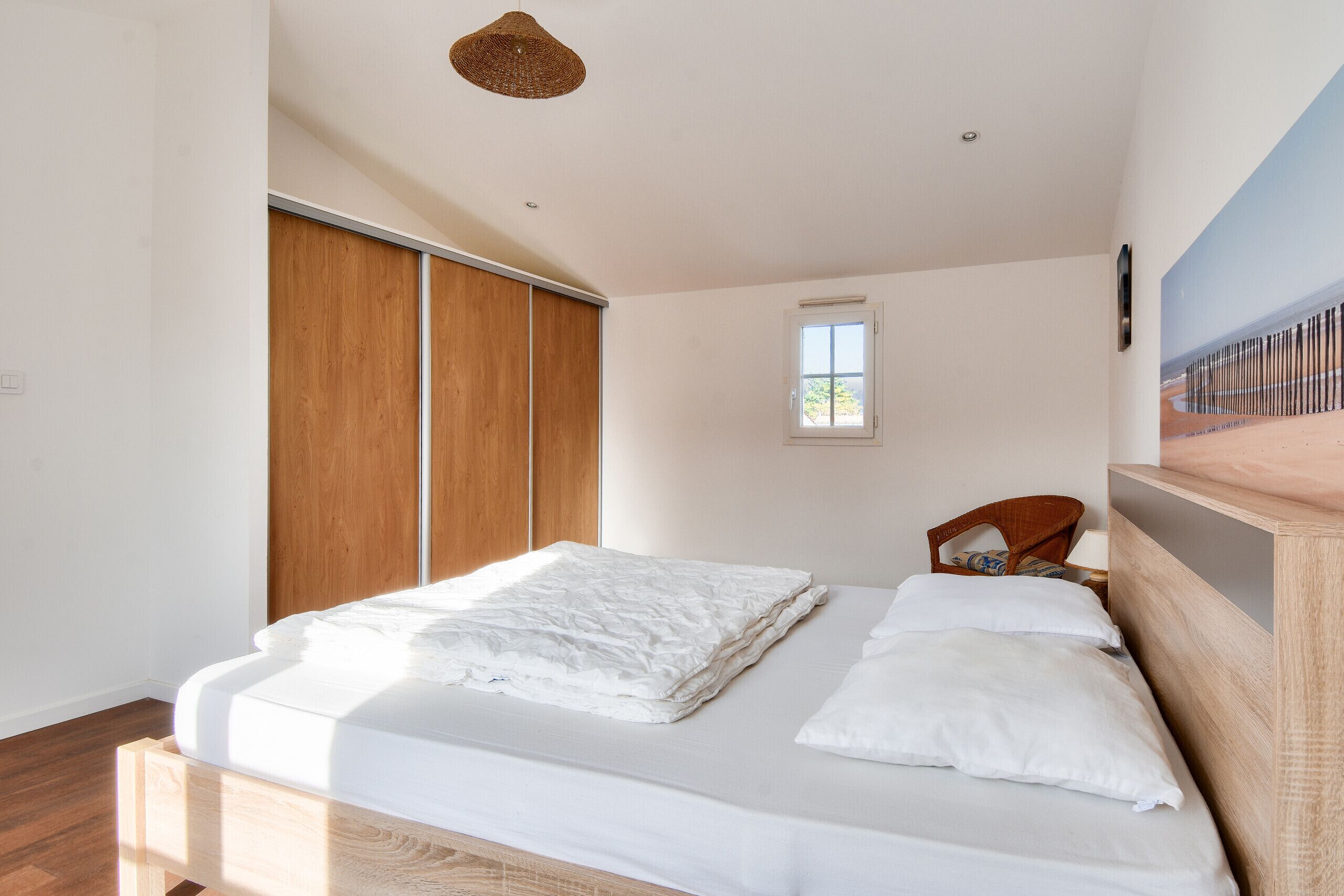 Un dormitorio con cama de madera, una ventana y estante fijado a la pared.