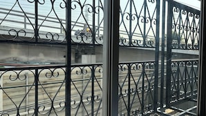 A view through a window with ornate iron railings, a concrete structure, and a metal staircase. - M3 Bangkok Bake & Bed (Bangkok)