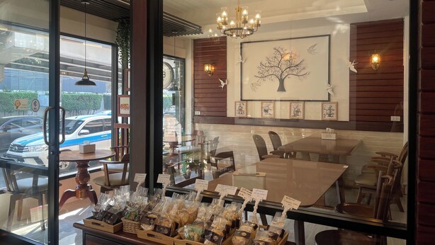 A restaurant interior with a dining area, a chandelier, and a wall with framed pictures. - M3 Bangkok Bake & Bed (Bangkok)