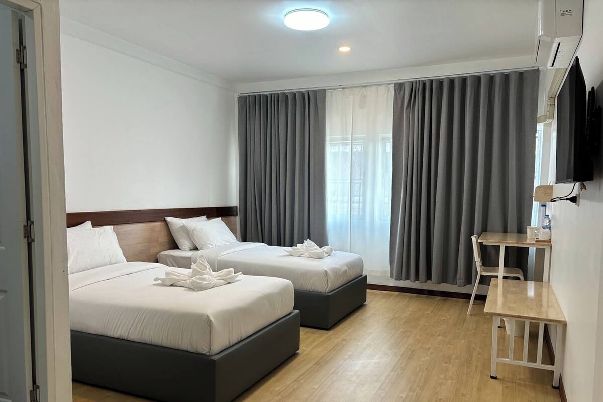 Une chambre d’hôtel avec deux lits, un bureau et une télévision.