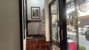 A hotel entrance with a glass door, a staircase leading inside, and a view of the street outside. - M3 Bangkok Bake & Bed (Bangkok)
