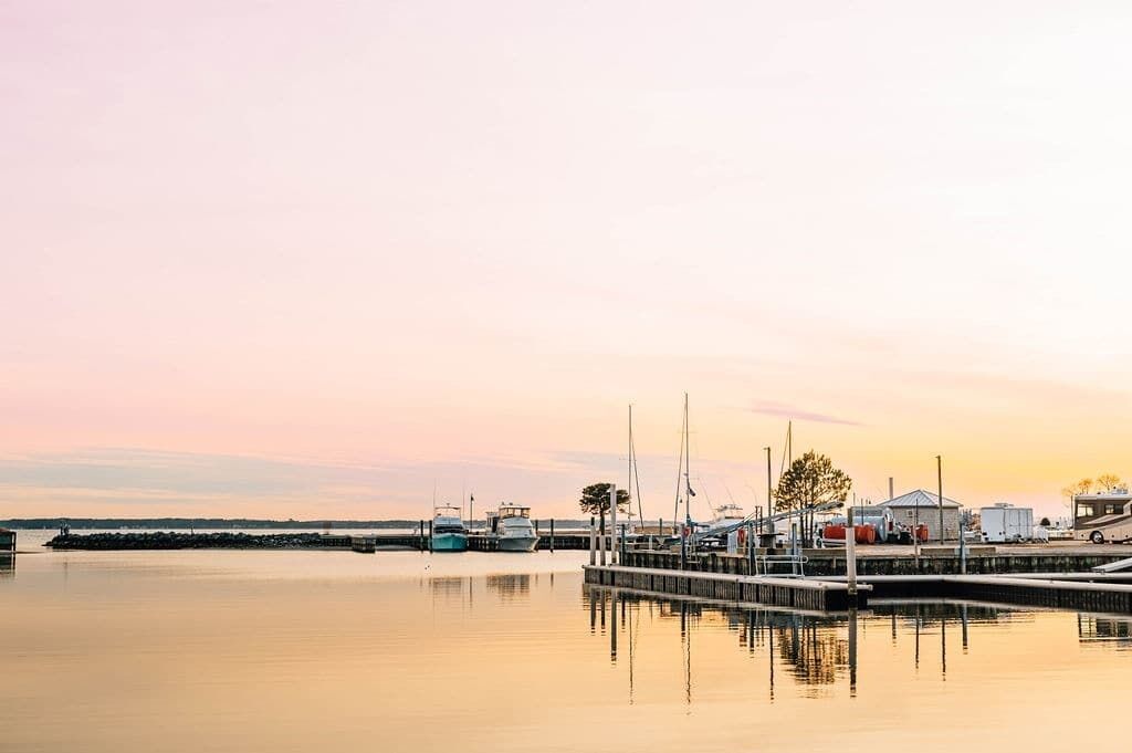 A marina with boats docked, a pier, and a small building.