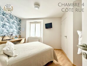 A bedroom with a bed, a desk, a chair, a TV, and a window. - Logis Hotel Restaurant Le Laurier Fleuri (Vertou)