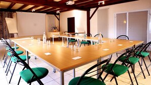 A conference room with a long table, green chairs, and a projector screen. - Logis Hotel Restaurant Le Laurier Fleuri (Vertou)