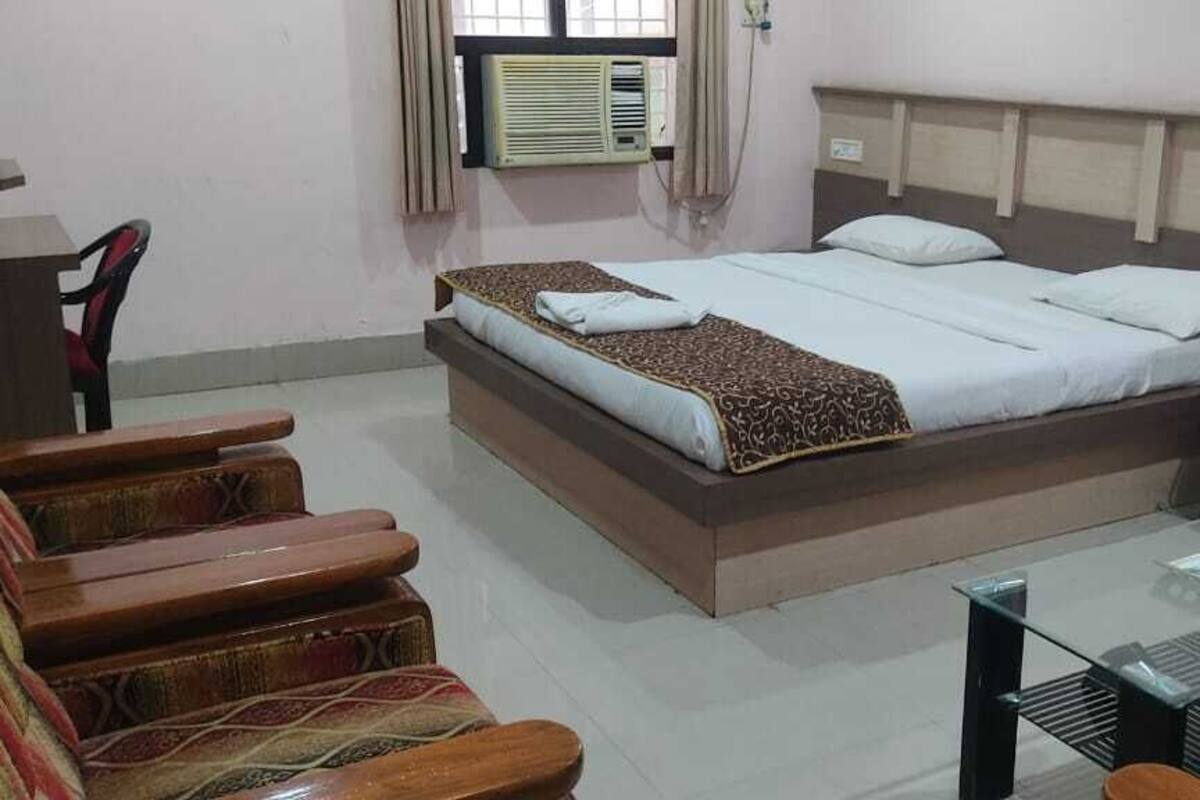 Una habitación de hotel con una cama, una mesa de centro de vidrio, una silla y un escritorio con una computadora.