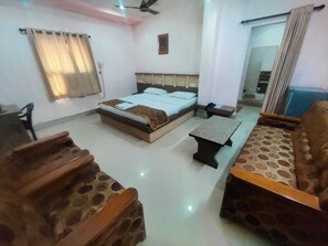 A room with a bed, a small table, a sofa, and a staircase. - Hotel Apsara Koraput (Jaypur)