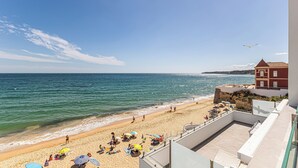 Une plage avec des gens, des parasols et un bâtiment.