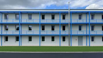 A multi-story motel with a flat roof, balconies, and a parking lot in front.