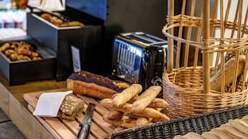 Variedad de panes y pasteles sobre una mesa de madera, un cuchillo y una tostadora.