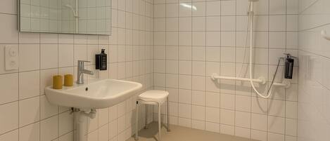 Un baño moderno con lavamanos, espejo y ducha blancos.