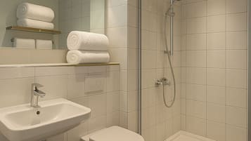 Un baño moderno con lavamanos, inodoro y ducha envuelta en vidrio.