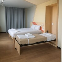 Una cama doble con estructura de madera, dos almohadas y una colcha.