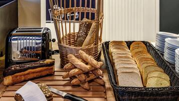 A variety of breads and a toaster on a wooden table.