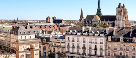 A historic city square with buildings, a prominent church, and a monument.