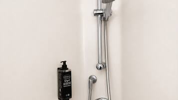 Ducha con cabezal de ducha de mano, grifo empotrado en la pared y dispensador de jabón manual.