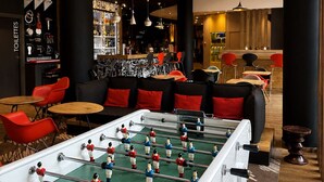 A foosball table in a modern lounge area with a bar and seating. - Ibis Budget Dijon Centre Clemenceau (Dijon)