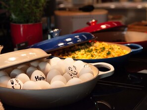 A kitchen with various cooking utensils and appliances, including a stove, pots, and a bowl of eggs with faces drawn on them. - Ibis Budget Berlin Airport (Berlin)