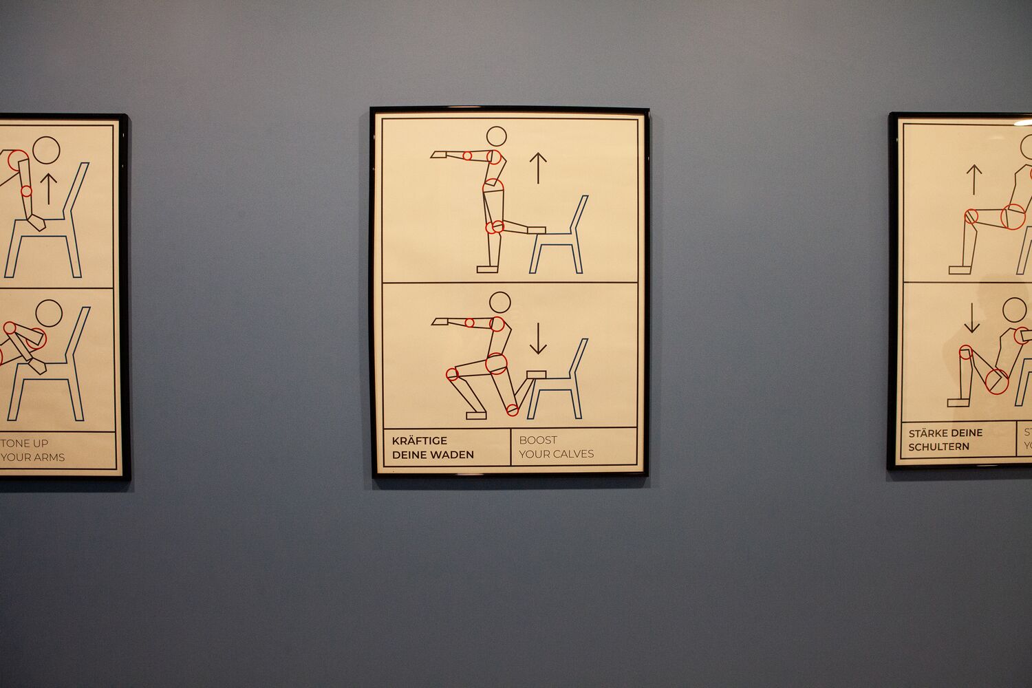 Trois affiches didactiques sont accrochées au mur, chacune représentant une figure illustrant différents exercices, accompagnées d’un texte explicatif en allemand.