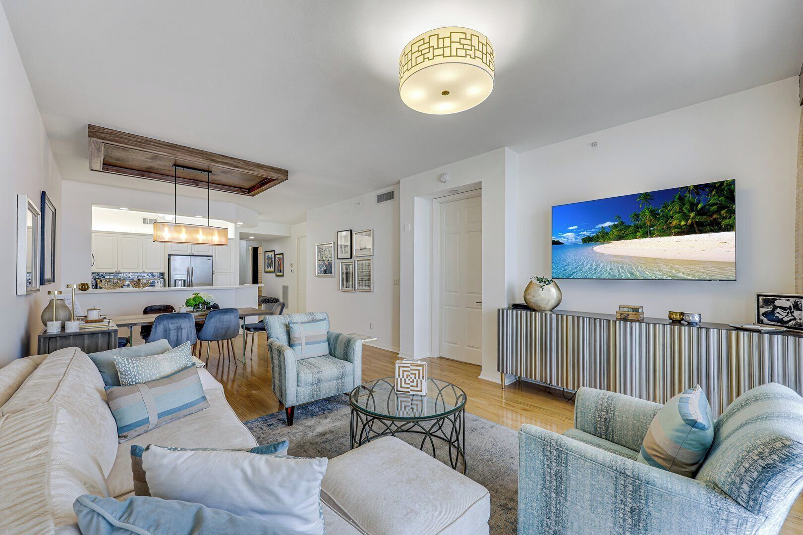A modern living room with a sofa, armchairs, a coffee table, and a TV mounted on the wall.
