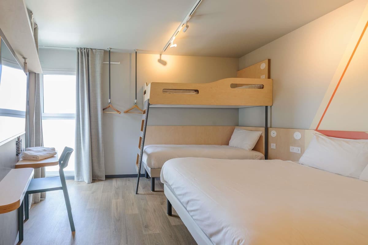 A bunk bed room with a desk and chair, a window with curtains, and a hanging light fixture.