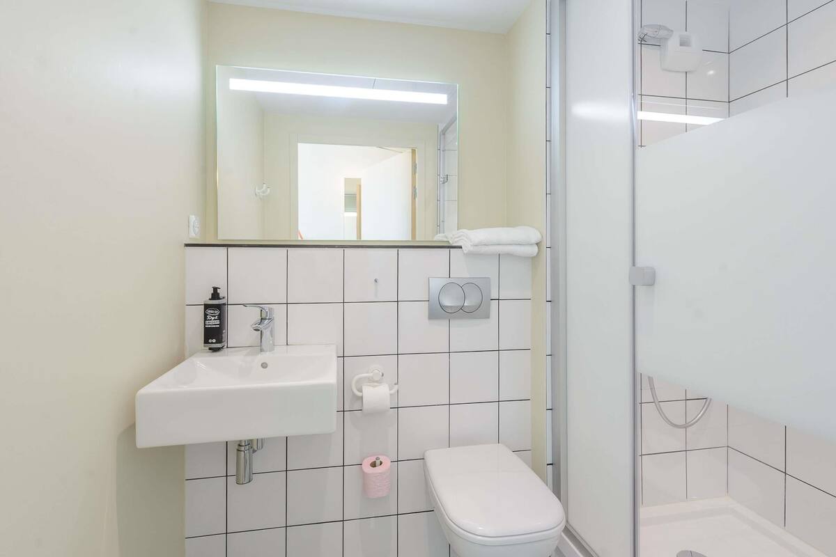 A modern bathroom with a white sink, toilet, and shower.