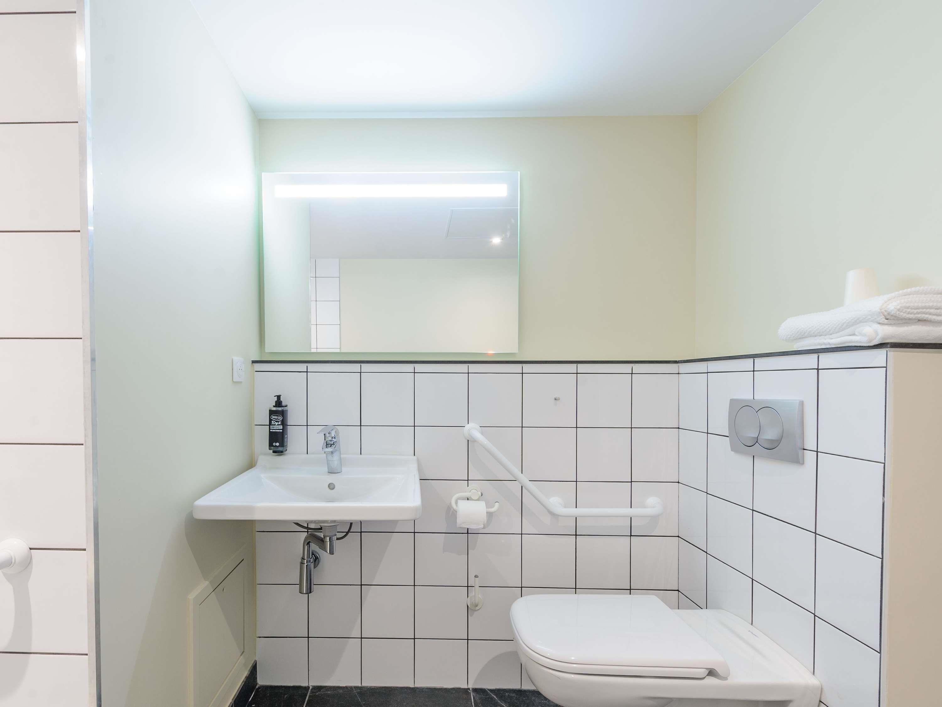 Baño con lavamanos blanco, inodoro y espejo.