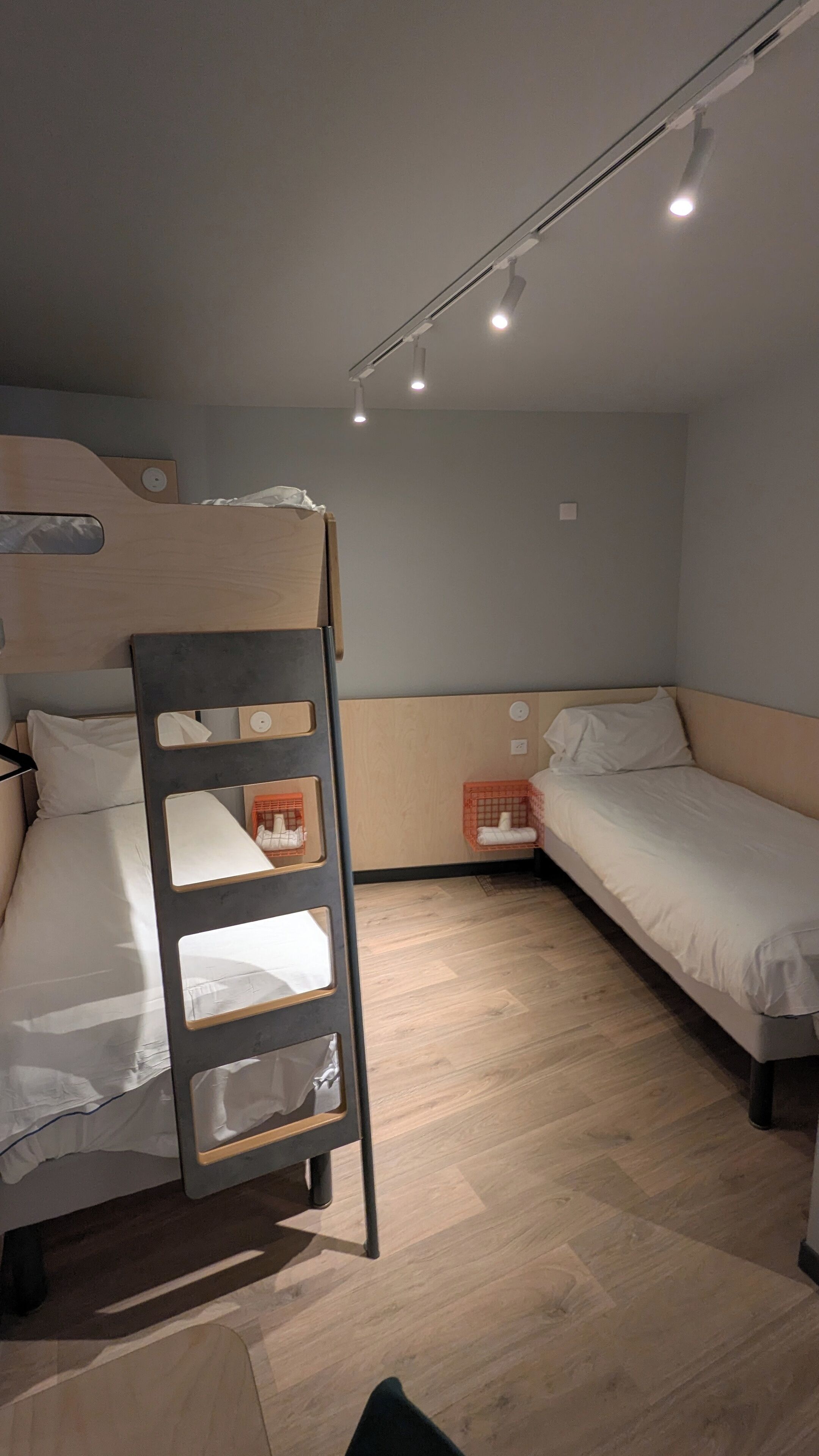 A room with two bunk beds, a wooden ladder, and a small orange basket on the floor.