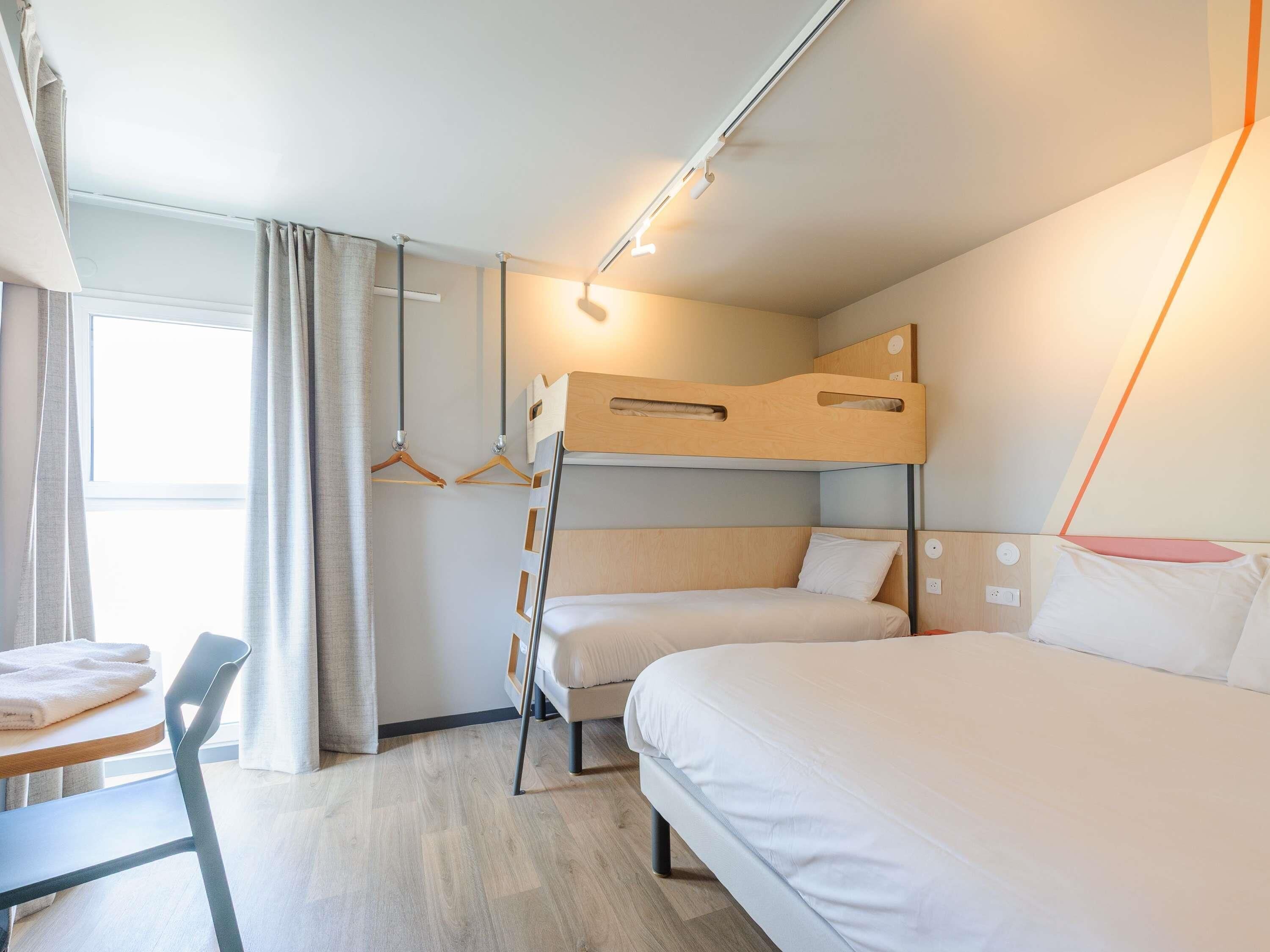 A hotel room with bunk beds, a desk, and a chair.