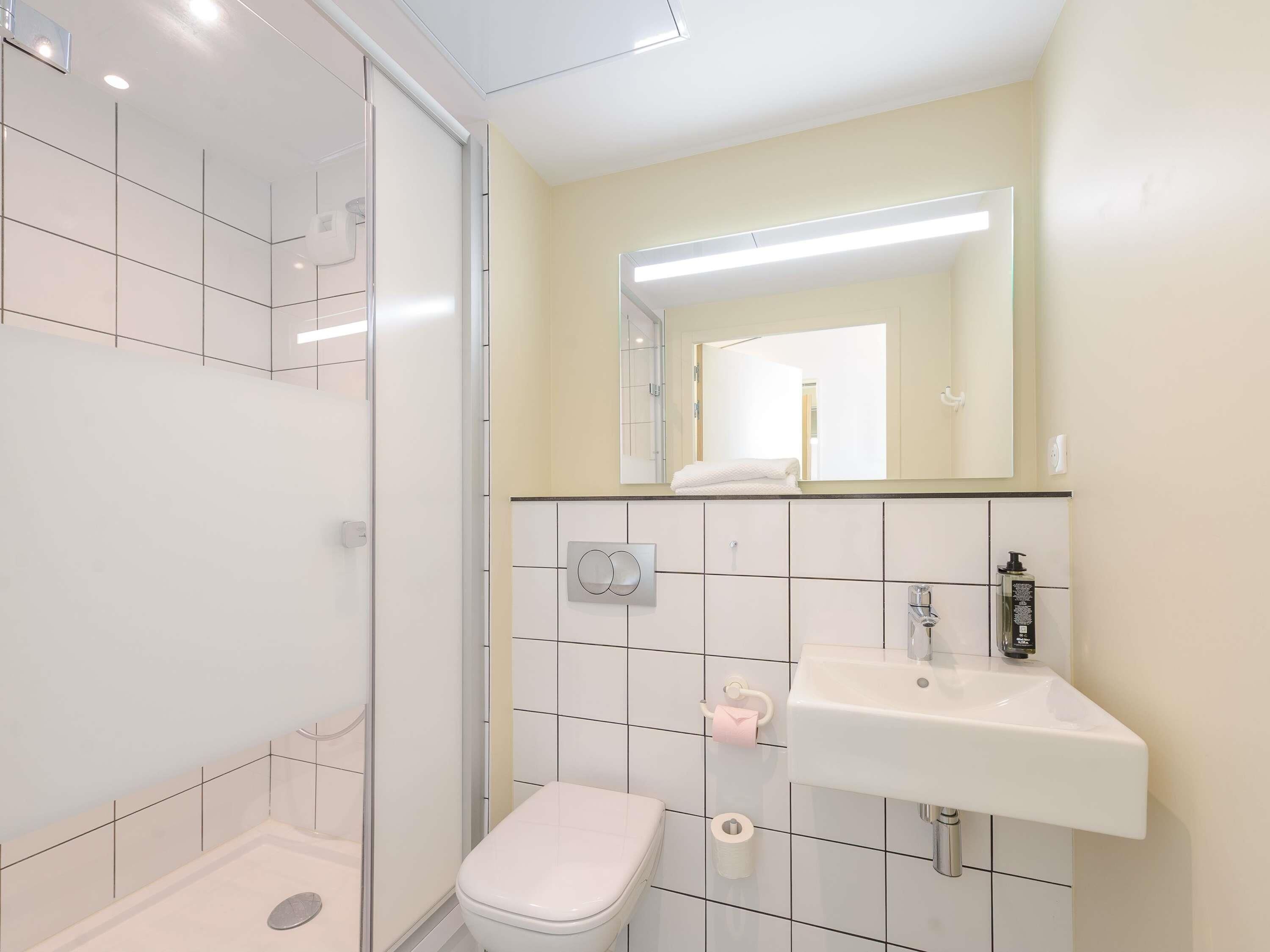 A modern bathroom with a shower, toilet, and sink.
