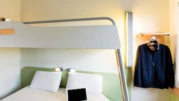 A bunk bed with a laptop on the lower bunk, a hanging garment, and a shelf with a light fixture.